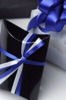 光沢のある黒の枕型箱に入れて青と白のシルクサテンリボンをかけます。さらに箱を上品な白の袋に収め、開いた花びらの形に結んだ青と銀のリボンをかけます。袋は水色の薄羽紙をふんわり敷いた白の外箱に入れてお送りいたします。箱を開けると清楚で凛とした美しさが広がります。