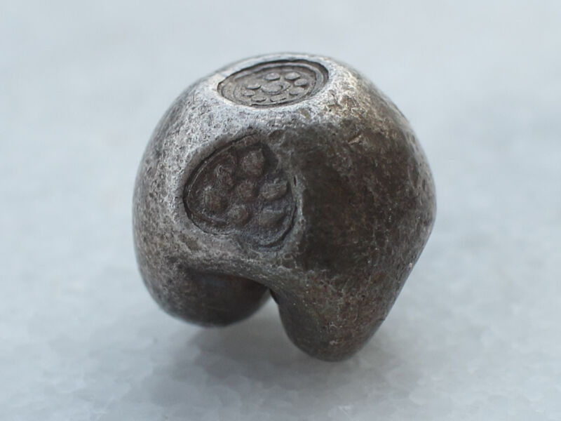 ポッドゥアン（弾丸コイン） - タカラ貝を模したタイの古銭。アユタヤ王朝で用いられたものでアユタヤ王朝のシンボル「法輪（ダルマチャクラ）」がトップに刻印されている。